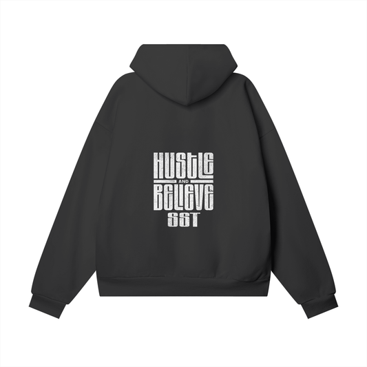 Black SST hoodie featuring 'Hustle' and 'Believe' text design on the back, oversized relaxed fit, warm brushed fleece lining, ribbed cuffs and hem for a snug fit.
